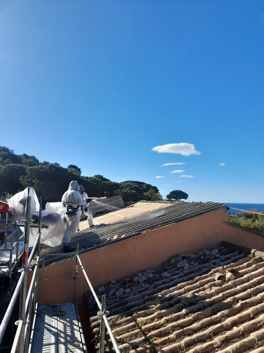 Techniciens MERCIER Environnement désamiantant une toiture face à la mer